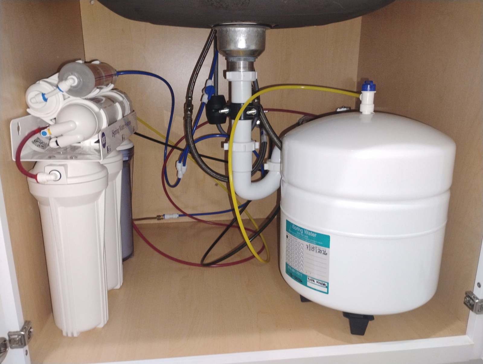 Completed under-sink reverse-osmosis installation with filter housings and storage tank
